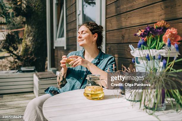 woman relaxing with herbal tea on porch of wooden cottage - zen bildbanksfoton och bilder