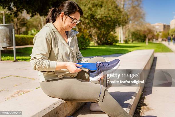 woman in sport clothes inserting insole in a running shoe. preparing for training - plantar fasciitis stock pictures, royalty-free photos & images