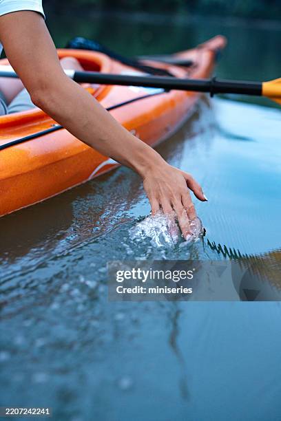close-up of hand touching water while kayaking on calm river - hand patting stock pictures, royalty-free photos & images