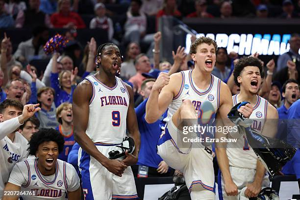 Rueben Chinyelu, Micah Handlogten and Walter Clayton Jr. #1 of the Florida Gators celebrate from the bench against the Maryland Terrapins during the...
