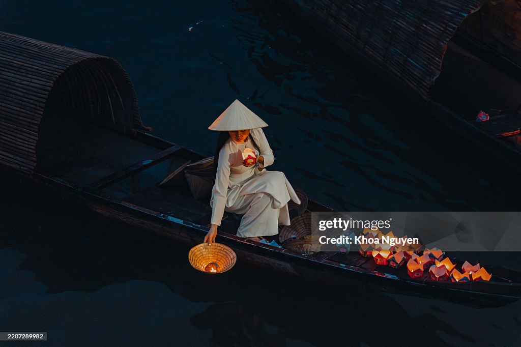 夜に川に浮かぶキャンドル付きの伝統的な色とりどりの提灯と、伝統的なベトナム文化を持つ美しい女性