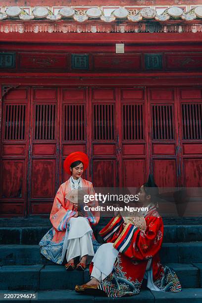 two young vietnamese woman wearing new year celebration dress called nhat binh in minh mang tomb, hue city, vietnam - traditional vietnam stock pictures, royalty-free photos & images