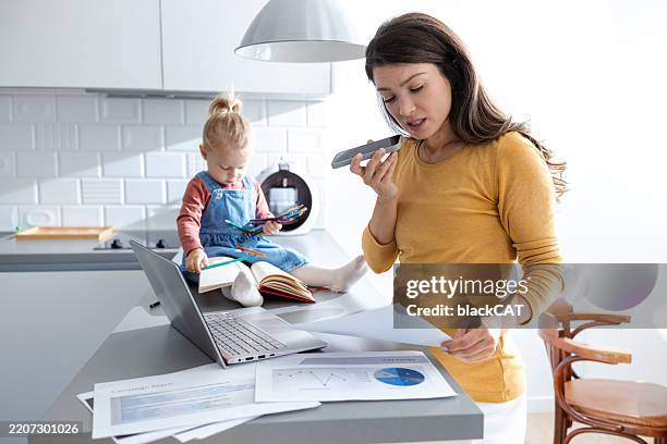 mother multitasking while toddler sits on the counter drawing with pencils - mãe trabalhadora imagens e fotografias de stock
