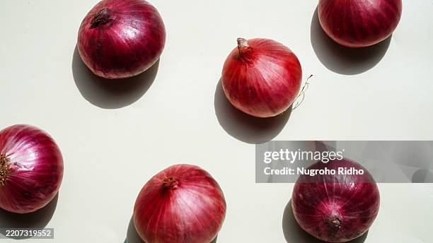 flat lay of red onion on white background, red vibrant color background - sjalot stockfoto's en -beelden
