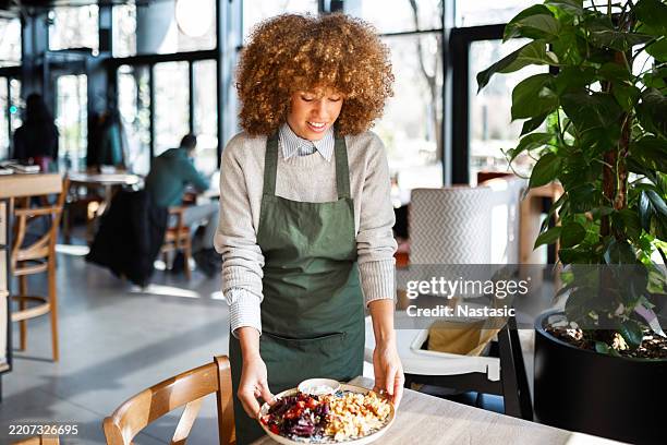 serveuse sympathique servant un délicieux repas avec le sourire - tablier photos et images de collection
