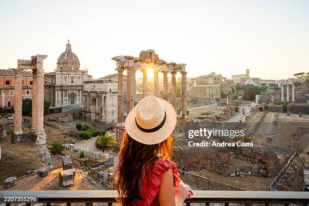 woman admiring roman forum ruins at sunrise in rome, italy. - romano imagens e fotografias de stock
