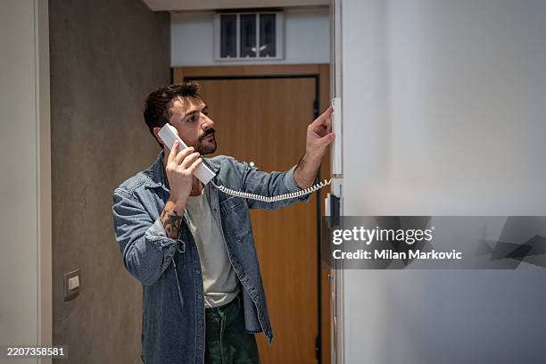 hombre usando el intercomunicador en casa mientras habla por teléfono - teléfono con cable fotografías e imágenes de stock