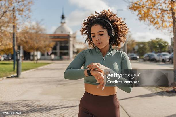 concentration while checking fitness tracker outdoors - checking the time stock pictures, royalty-free photos & images