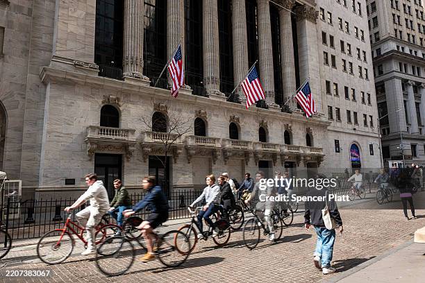 Tourists ride bicycles past the New York Stock Exchange in lower Manhattan on March 28 in New York City. A new report by the research firm Tourism...