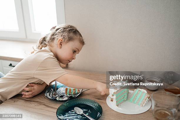 little girl with cochlear implant reaching for another slice of turquoise birthday cake in the kitchen - layer cake stock pictures, royalty-free photos & images