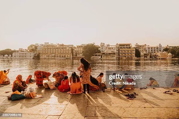 group of women on riverside in traditional clothing in indian cityscape - udaipur india stock pictures, royalty-free photos & images