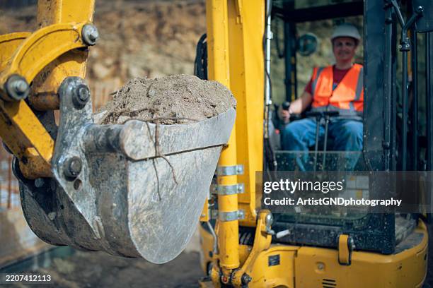 cheerful excavator driver digging trench at construction site. - mechanical digger stock pictures, royalty-free photos & images