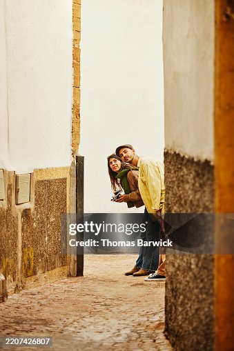 Extreme wide shot couple looking around corner in the old medina Extreme wide shot couple looking around corner in the old medina