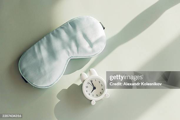 morning relaxation essentials with eye mask and small white alarm clock - eye mask stock pictures, royalty-free photos & images