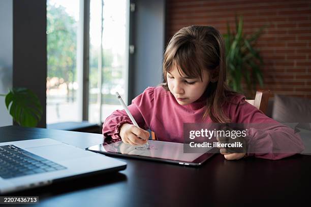 child girl watching online tutorial on laptop computer and drawing digital pictures using digitized pen and digital tablet - graphics tablet stock pictures, royalty-free photos & images