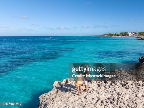 Couple Enjoying Scenic Coastal View from Rocky Shoreline Couple Enjoying Scenic Coastal View from Rocky Shoreline