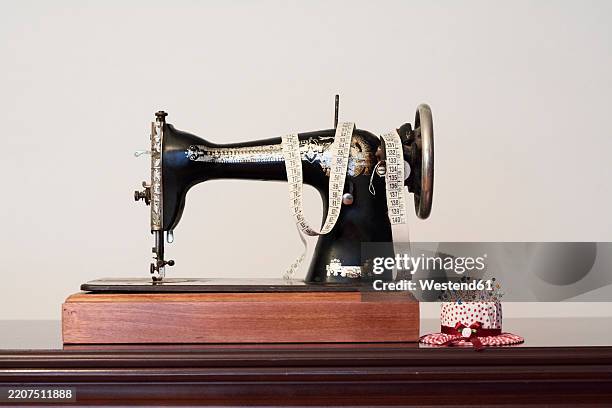 old vintage sewing machine with measuring tape and pin chusion in shape of a hat - sewing machine stock pictures, royalty-free photos & images
