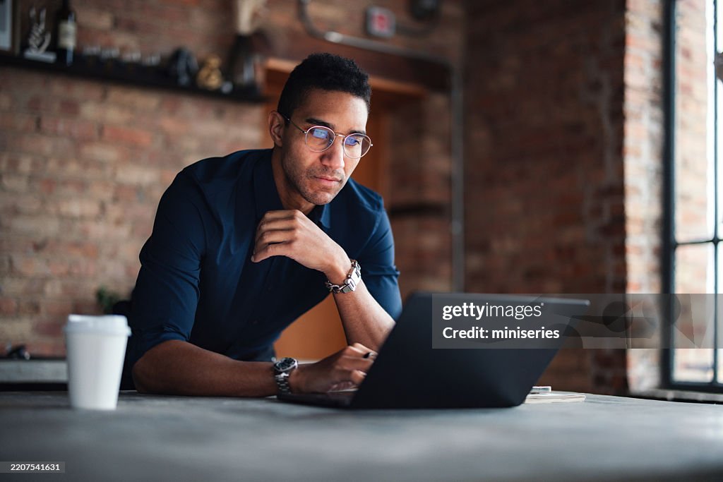 Focused Professional Working on Laptop in a Modern Brick Office Space