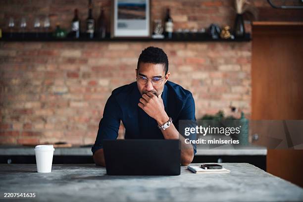 professionista concentrato che lavora su un laptop in uno spazio di lavoro moderno ed elegante - occhiali da lettura foto e immagini stock