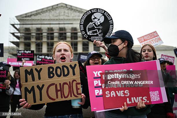 Supporters of Planned Parenthood, with an anti-abortion activist counterprotesting behind them, rally outside the US Supreme Court on April 2 in...