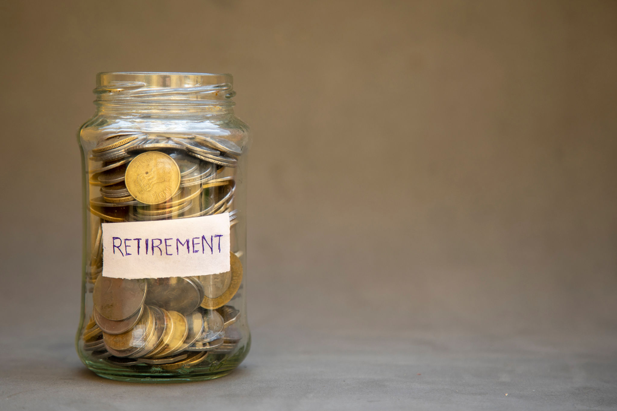 Glass Jar with Coins Labeled Retirement Suggesting Future Savings and Financial Planning. Glass Jar with Coins Labeled Retirement Suggesting Future Savings and Financial Planning.