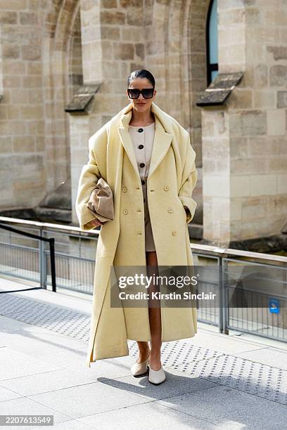 Gili Biegun wears a DISSH dress, Flattered bag, Celine sunglasses, Choux coat and scarf and cream kitten heeled shoes outside the Akris show during...