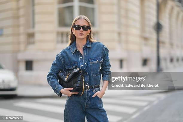 Diane Batoukina wears sunglasses from YSL Saint-Laurent, earrings, a blue Anine Bing denim shirt with long sleeves, Anine Bing blue denim pants /...
