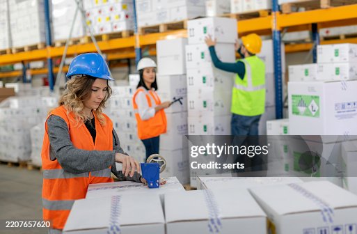 Warehouse team performing packaging, stacking, and loading tasks in a busy logistics facility. Warehouse team performing packaging, stacking, and loading tasks in a busy logistics facility.