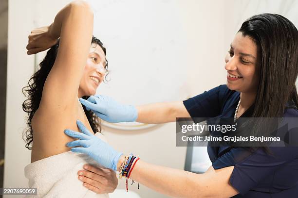 dermatologist examining patient's armpit for skin cancer screening - under the arm stock pictures, royalty-free photos & images