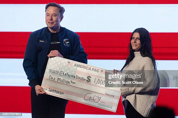 Billionaire businessman Elon Musk gives $1 000 to a Wisconsin voter, Ekaterina Diestler, during a town hall meeting he was hosting at the KI...
