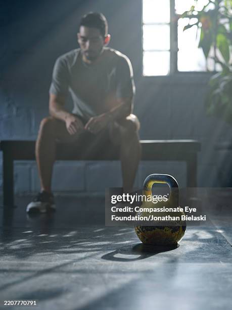 man resting between kettlebell exercises at gym - sportplaats stockfoto's en -beelden