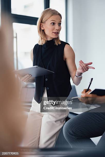 professional woman leading a discussion in a modern office setting - delegating stock pictures, royalty-free photos & images