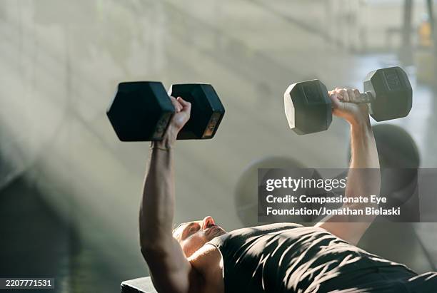 young man lifting heavy dumbbells in gym - self-discipline stock pictures, royalty-free photos & images