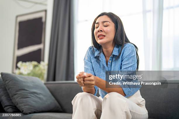 upset woman sitting on a sofa in a modern interior setting - terrified stock pictures, royalty-free photos & images