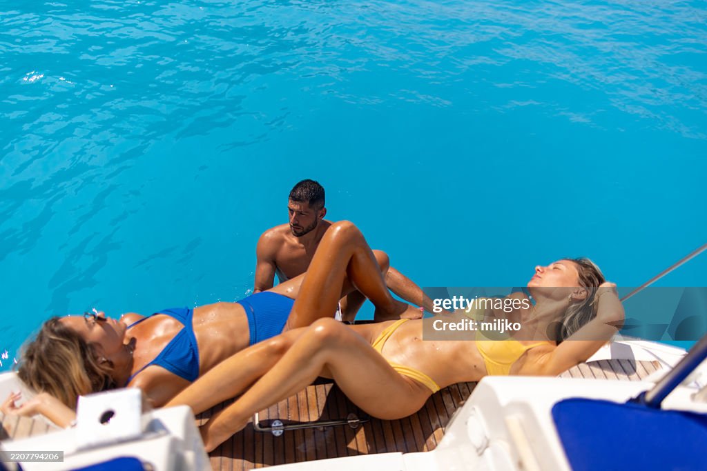 Group Of Friends Sunbathing At Stern Of A Sailboat High Res Stock Photo diverse-group-of-friends-sunbathing-together-by-pool-on-a-sunny-day