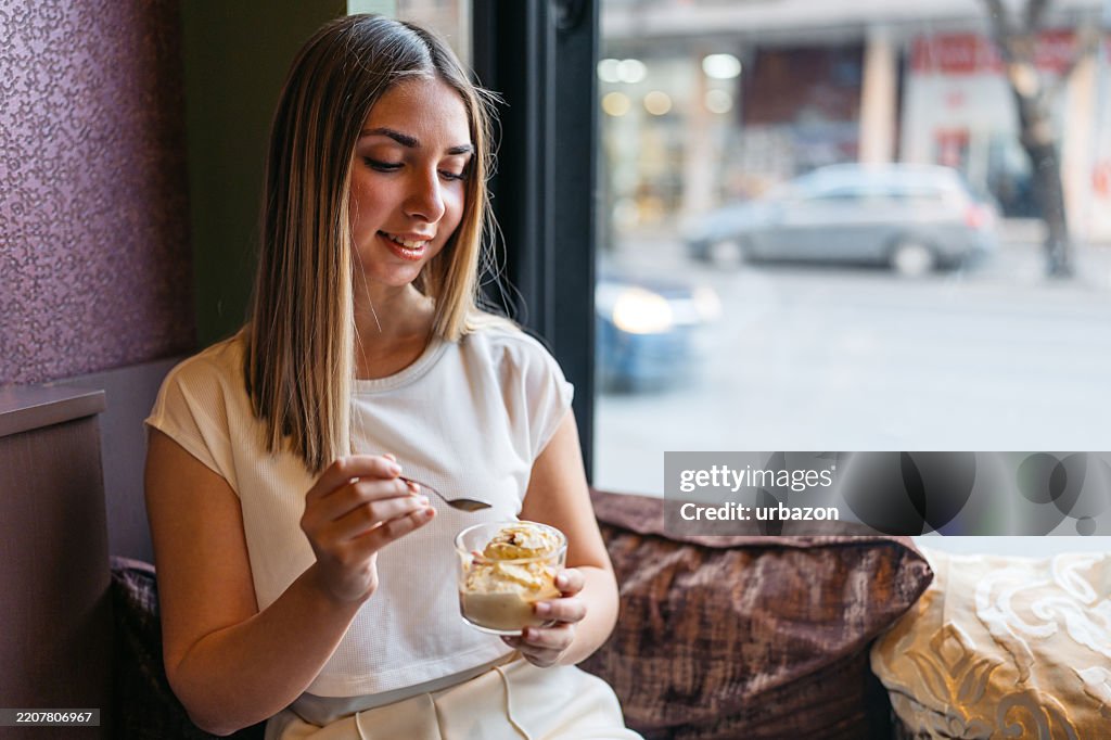 屋内のコーヒーショップでアフ��ォガートを食べている若い女性