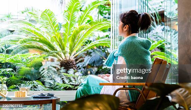 casual beautiful woman sitting in the cafe with many greet plants - sago drink stock pictures, royalty-free photos & images