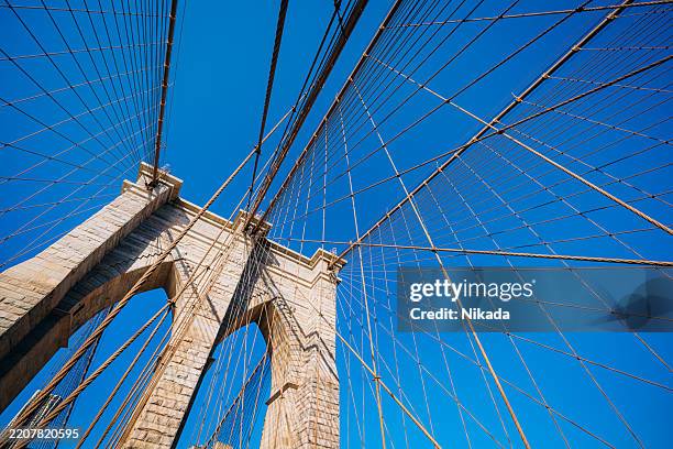 architectural view of the brooklyn bridge against a vibrant blue sky - symbolism stock pictures, royalty-free photos & images