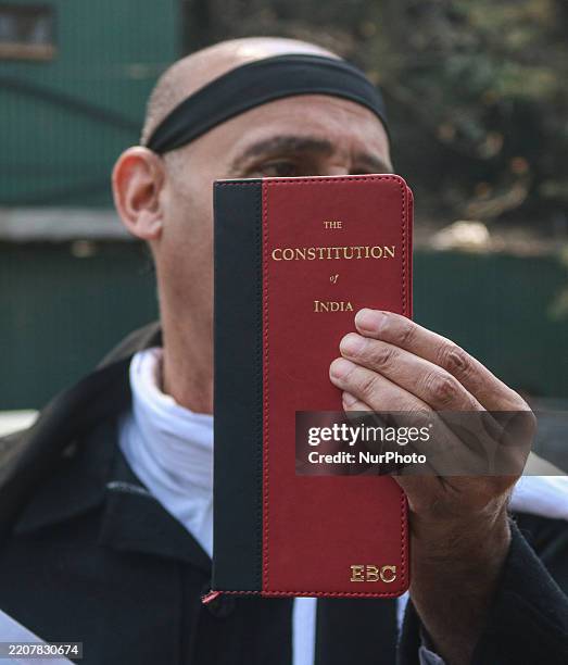 Member of the Legislative Assembly of Jammu and Kashmir, Irfan Hafiz Lone, holds a copy of the Indian Constitution as he protests against the Waqf...