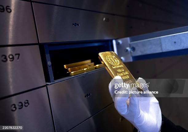 April 2025, Bavaria, Munich: A man places a gold bar in a safe deposit box in a vault at the precious metal dealer Pro Aurum. Photo: Sven Hoppe/dpa