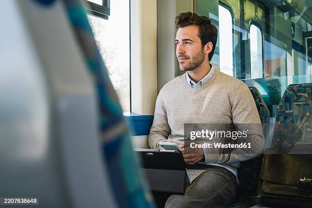 young man with smartphone and tablet on a train - train vehicle stock pictures, royalty-free photos & images
