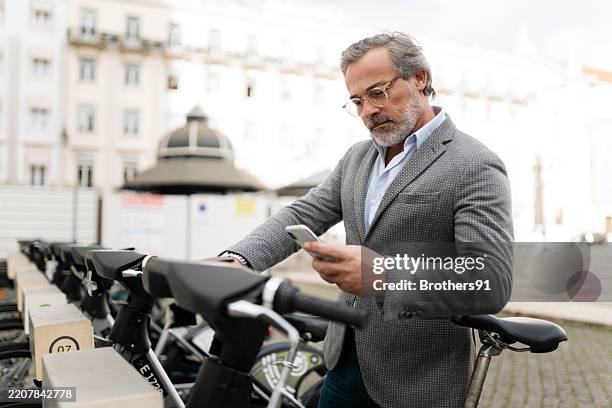 businessman using smartphone to rent a bike in a sharing system - sharing economy stock pictures, royalty-free photos & images