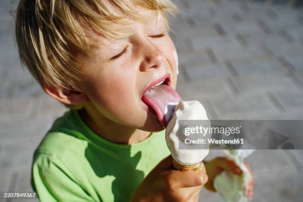 blonde child enjoying ice cream outdoors on a sunny day - geada imagens e fotografias de stock