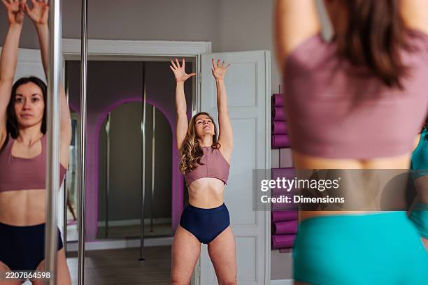 young women practicing pole dance exercising in a gym - pole dance stock pictures, royalty-free photos & images