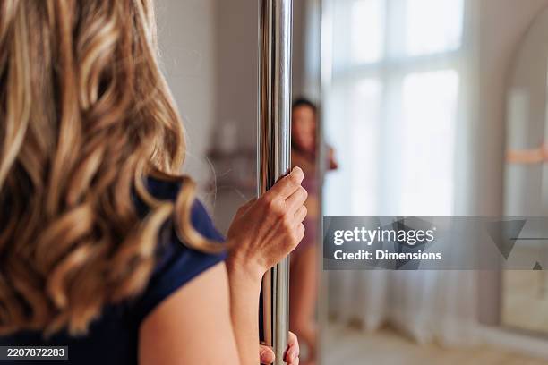 woman practicing pole dance holding a pole bar - pole dance stock pictures, royalty-free photos & images