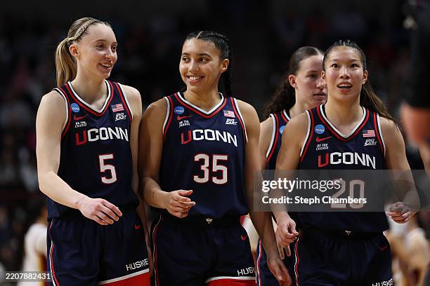Paige Bueckers, Azzi Fudd and Kaitlyn Chen of the UConn Huskies walk to the bench during the second half against the USC Trojans in the Elite Eight...