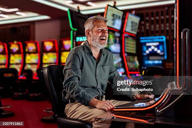 lächelnder mann, der ein casino-spielautomaten-spielerlebnis genießt - kasino stock-fotos und bilder
