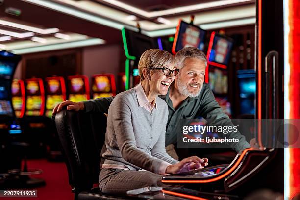 couple de personnes âgées profitant de jeux de casino ensemble dans une atmosphère de jeu vibrante - casino interior photos et images de collection