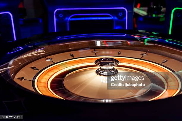 beleuchtetes roulette-rad in einer farbenfrohen casino-umgebung, die spannung einfängt - glücksrad stock-fotos und bilder