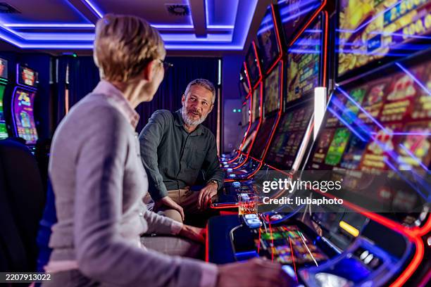 couple profitant des machines à sous dans un casino - casino interior photos et images de collection